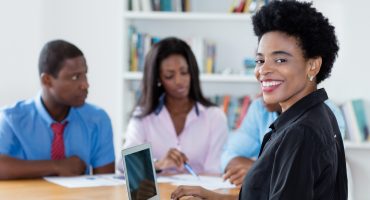 Smart african american businesswoman with team and computer at office of new business company