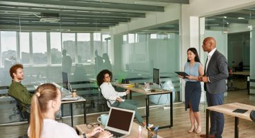 Focused black male company boss and his assistant listen question from caucasian male employee during business meeting. Multiracial people in office. Concept of business leadership and management